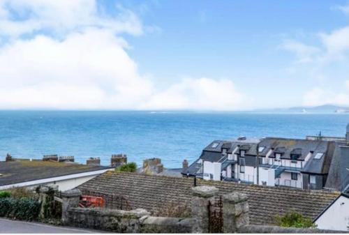 uma grande casa branca com o oceano ao fundo em ABOVE ST IVES PORTHMINSTER BEACH - "St James Rest" is a REFURBISHED & SUPER STYLISH PRIVATE APARTMENT - King Bedroom with Ensuite, Family Bathroom, Double Bunk Cabin & Sofabed LoungeKitchenDiner - 2 mins walk Main Car Park & Station em St. Ives