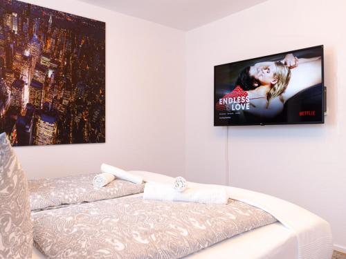 a flat screen tv hanging on a wall above a bed at Stylish apartment - 3 Min walk to Wuppertal main train station - Close to the University - Kitchen - Netflix in Wuppertal