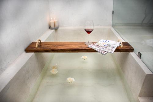 a bath tub with a glass of wine and a newspaper at Areval Hotel Boutique de Lago & Eventos in San Cristóbal Zapotitlán