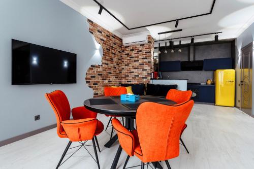 a dining room with a black table and orange chairs at VIP apartments with sea view in Odessa in Odesa