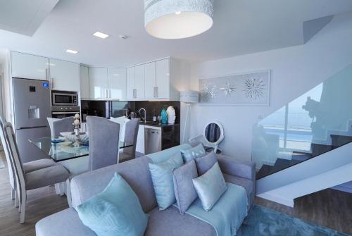 a living room with a blue couch and a kitchen at Villa Atlantic Charm in Venda do Atalhinho