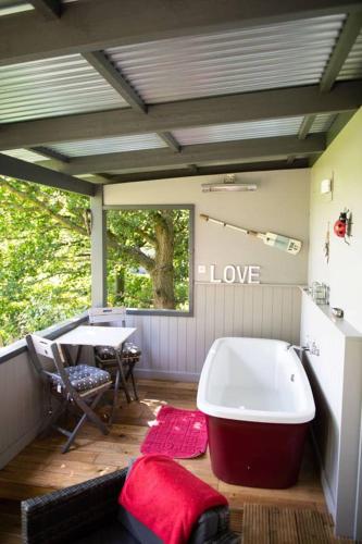 a bathroom with a tub on a deck with a table at Thompson Hall Retreat in Thompson