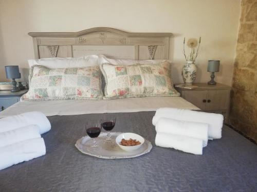 a bed with a plate of food and two glasses of wine at Agriturismo Fondo Paliemmu in Modica