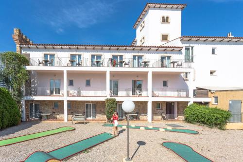 a woman standing in front of a large building at Hotel Castell Blanc in Empuriabrava