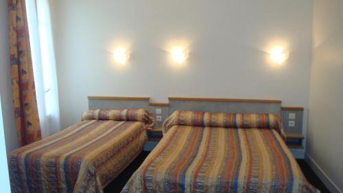 two beds in a room with lights on the wall at Hotel des Vosges in Paris