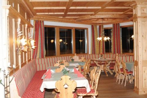 a dining room with tables and chairs and windows at Hotel Humlerhof in Gries am Brenner