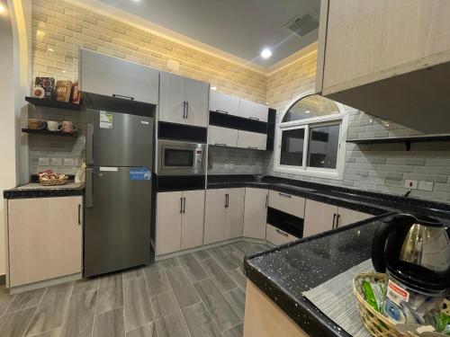 a kitchen with a stainless steel refrigerator and white cabinets at Luxury OVO Roof Villa in Taif