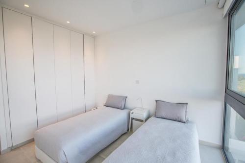 two beds in a room with a window at The White H Villa, Protaras, Fresh and Peaceful in Paralimni