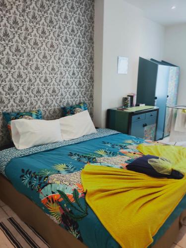 une chambre avec un lit avec une couverture jaune dans l'établissement Blanc de Tardy, à Saint-Étienne