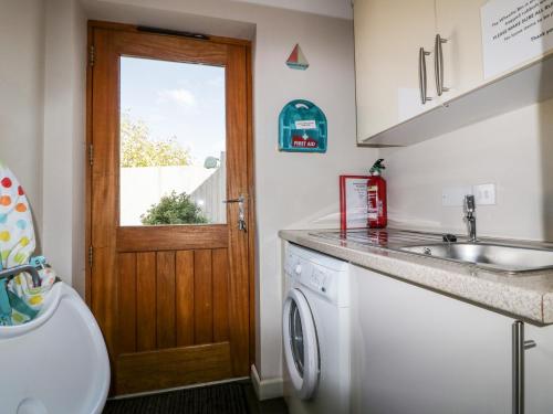 a kitchen with a sink and a washing machine at Carpe Diem in Crantock