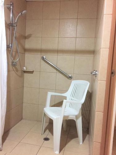 a white chair in a bathroom with a shower at Hotel Villablanca in Tehuacán