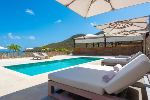 a pool with chaise lounge chairs and an umbrella at Le Domaine Anse Marcel Beach Resort in Anse Marcel 
