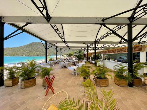 a restaurant with tables and chairs and a beach at Le Domaine Anse Marcel Beach Resort in Anse Marcel 