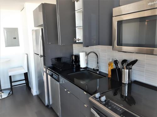 a kitchen with a sink and a microwave at Cozy Skyline Condo in Downtown, across Canada Life Centre in Winnipeg