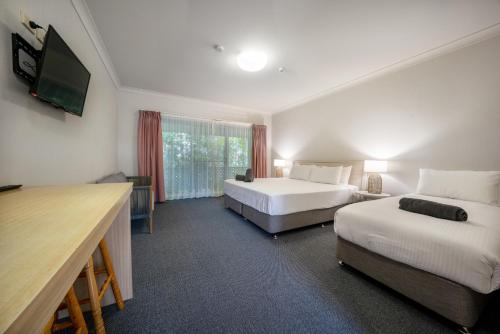 a hotel room with two beds and a flat screen tv at Woolgoolga Coast Motel in Woolgoolga