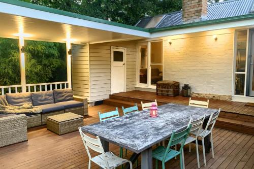 a patio with a table and chairs and a couch at Illalangi Boutique Cottage in Blackheath