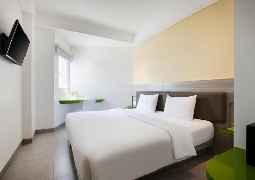 a bedroom with a large white bed and a television at Amaris Hotel Kupang in Kupang