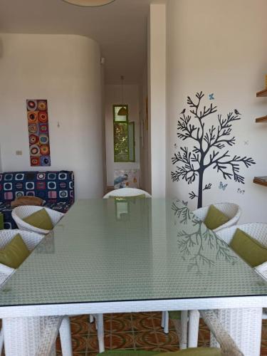 a dining room table with a tree stencil on the wall at Casa Roby 120 mt Beach in Fontane Bianche