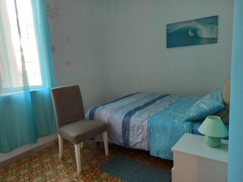 a bedroom with a bed and a chair and a window at Casa Roby 120 mt Beach in Fontane Bianche