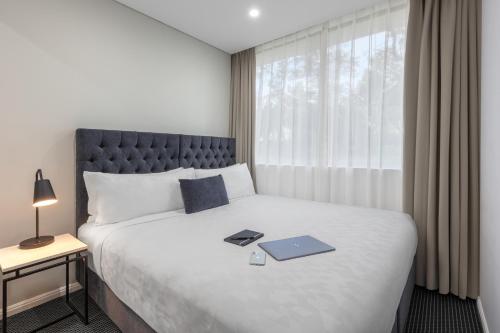 a bedroom with a large bed and a large window at Meriton Suites North Ryde in Sydney