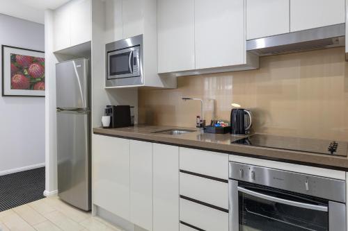 a kitchen with a stove, microwave and refrigerator at Meriton Suites North Ryde in Sydney