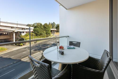 a table and chairs on a balcony with a view of a street at Meriton Suites North Ryde in Sydney