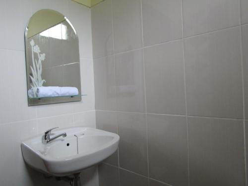 ein weißes Badezimmer mit einem Waschbecken und einem Spiegel in der Unterkunft Anang Bed & Breakfast Syariah by Ndalem Beong in Magelang