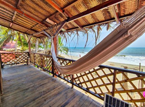 a porch with a hammock on the beach at Hostal halaliku in Santa Marta