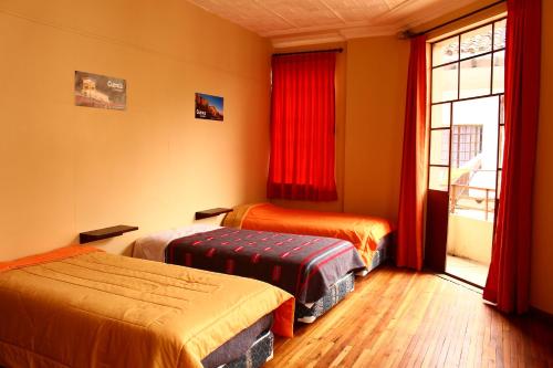 um quarto com duas camas e uma janela com cortinas vermelhas em Check Inn Bed and Breakfast em Cuenca