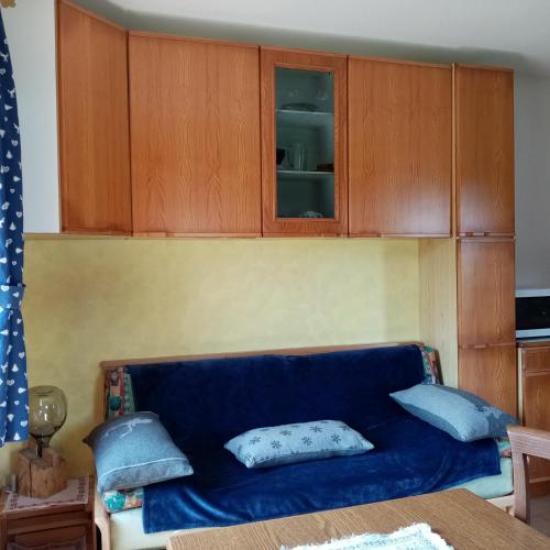 a blue couch in a kitchen with wooden cabinets at Appartamento Piller Roner Paola in Sappada