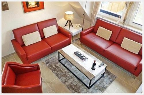 Sala de estar con 2 sofás rojos y mesa de centro en 4-ZIMMER-FERIENWOHNUNG DEICHWIESE -Westerland-Sylt - Garten - Terrasse - 3 Schlafzimmer - 2 - 5 Pers, en Westerland