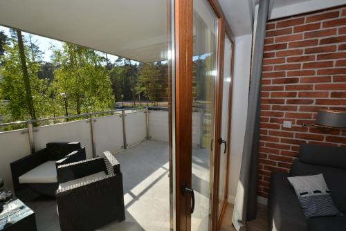 uma varanda com portas de vidro deslizantes e uma parede de tijolos em Apartment Premium Wood Baltic Park - 58m2, 3 pokoje em Stegna