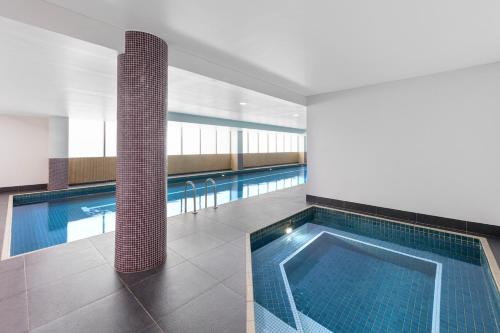 a large swimming pool with a tile floor and a swimming pool at Meriton Suites North Ryde in Sydney