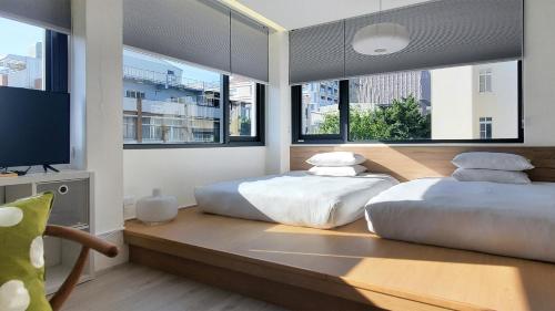 two beds in a room with large windows at Little Inn by LAGOM in Kaohsiung