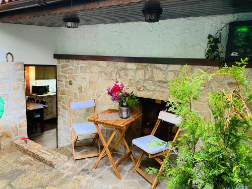 un patio con mesa, sillas y pared de piedra. en Бургасский дом en Burgas