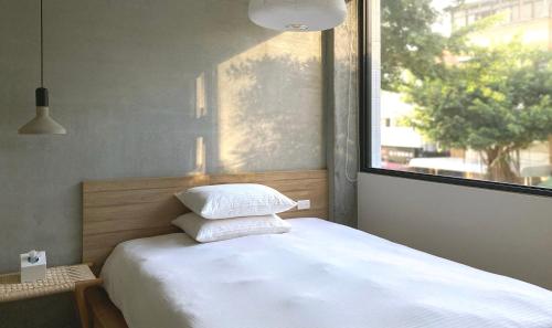 a bed in a room with a large window at Little Inn by LAGOM in Kaohsiung