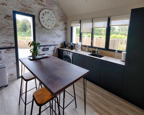 une cuisine avec une table et une horloge au mur dans l'établissement La maison de Jean, à Milizac