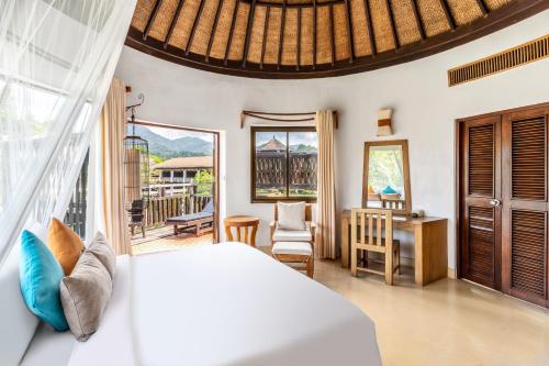 a bedroom with a bed and a desk and a balcony at AANA Resort & Villas Koh Chang in Ko Chang