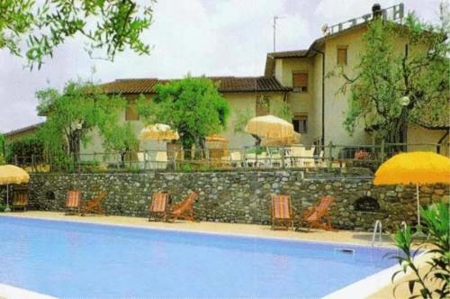 a swimming pool in front of a house with chairs and umbrellas at Hotel Ismaele in Chiusi