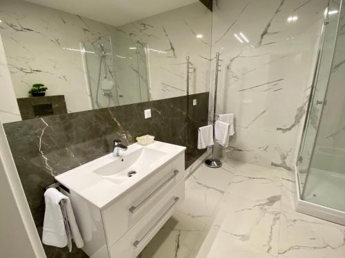 biała łazienka z umywalką i prysznicem w obiekcie Fischer Apartments w mieście Międzyzdroje