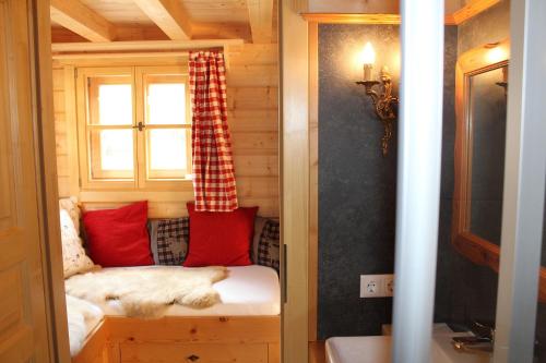 a tiny house with a window and red pillows at Schlosswirt Chalets & Apartments in Großkirchheim