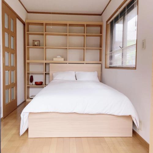 a bedroom with a large white bed and a window at Young House in Matsudo
