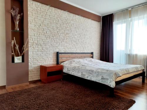 een slaapkamer met een bed en een bakstenen muur bij Староярмаркова с видом на парк и реку in Krivoy Rog