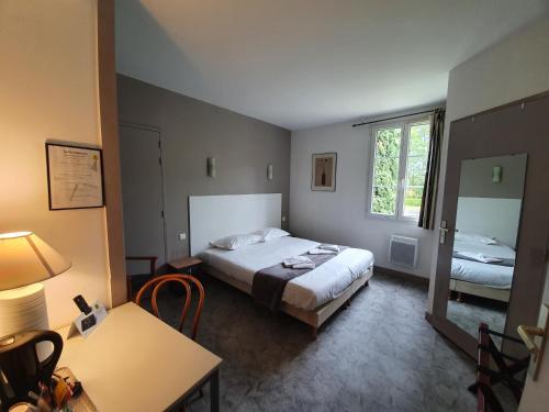 a bedroom with a bed and a table and a mirror at Hôtel Restaurant La Promenade in Gourdon-en-quercy