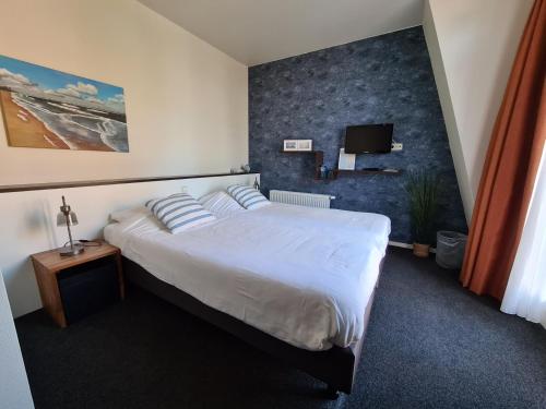 a bedroom with a large bed and a tv at Boutique Hotel De Raetskamer in Noordwijkerhout