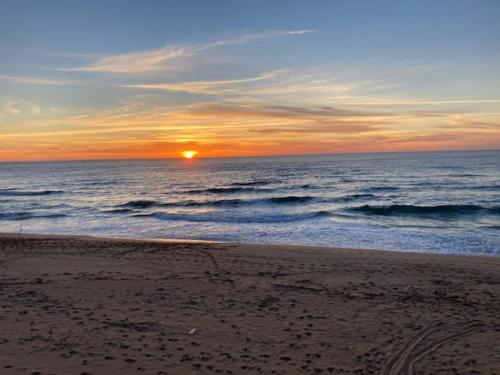 a sunset on a beach with the ocean at Buggerru a Mare Residence in Buggerru