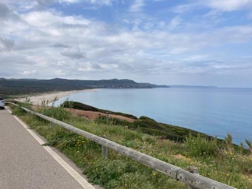 a road next to a beach with a body of water at Buggerru a Mare Residence in Buggerru