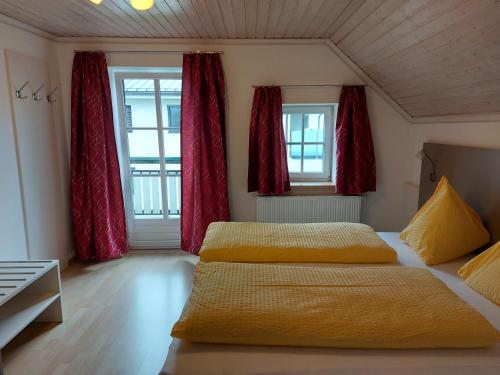 2 camas en una habitación con cortinas rojas en K3 Ferienhaus en Strobl