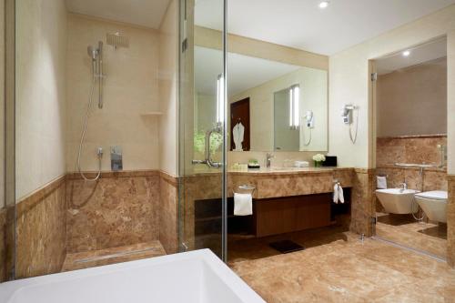 y baño con ducha y lavamanos. en Royal Tulip Muscat en Mascate