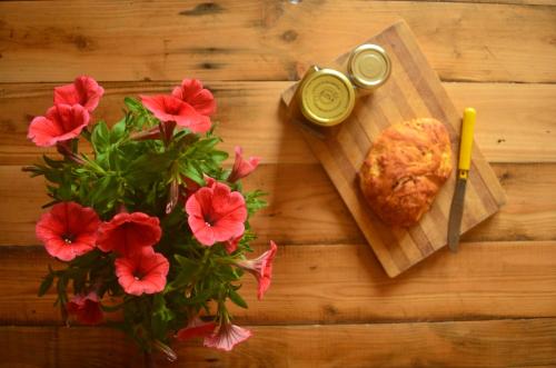 a wooden table with a cutting board with a sandwich and flowers at B&B Terra e Paglia in SantʼAnna